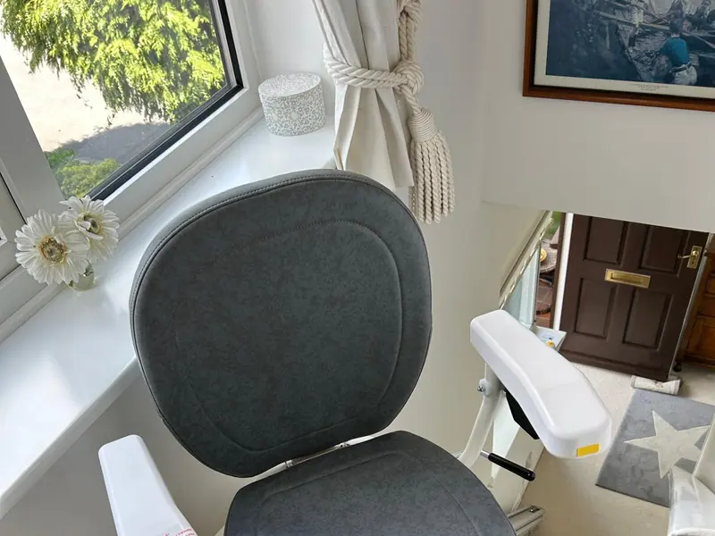 Close-up of a modern stairlift seat with padded backrest and armrests